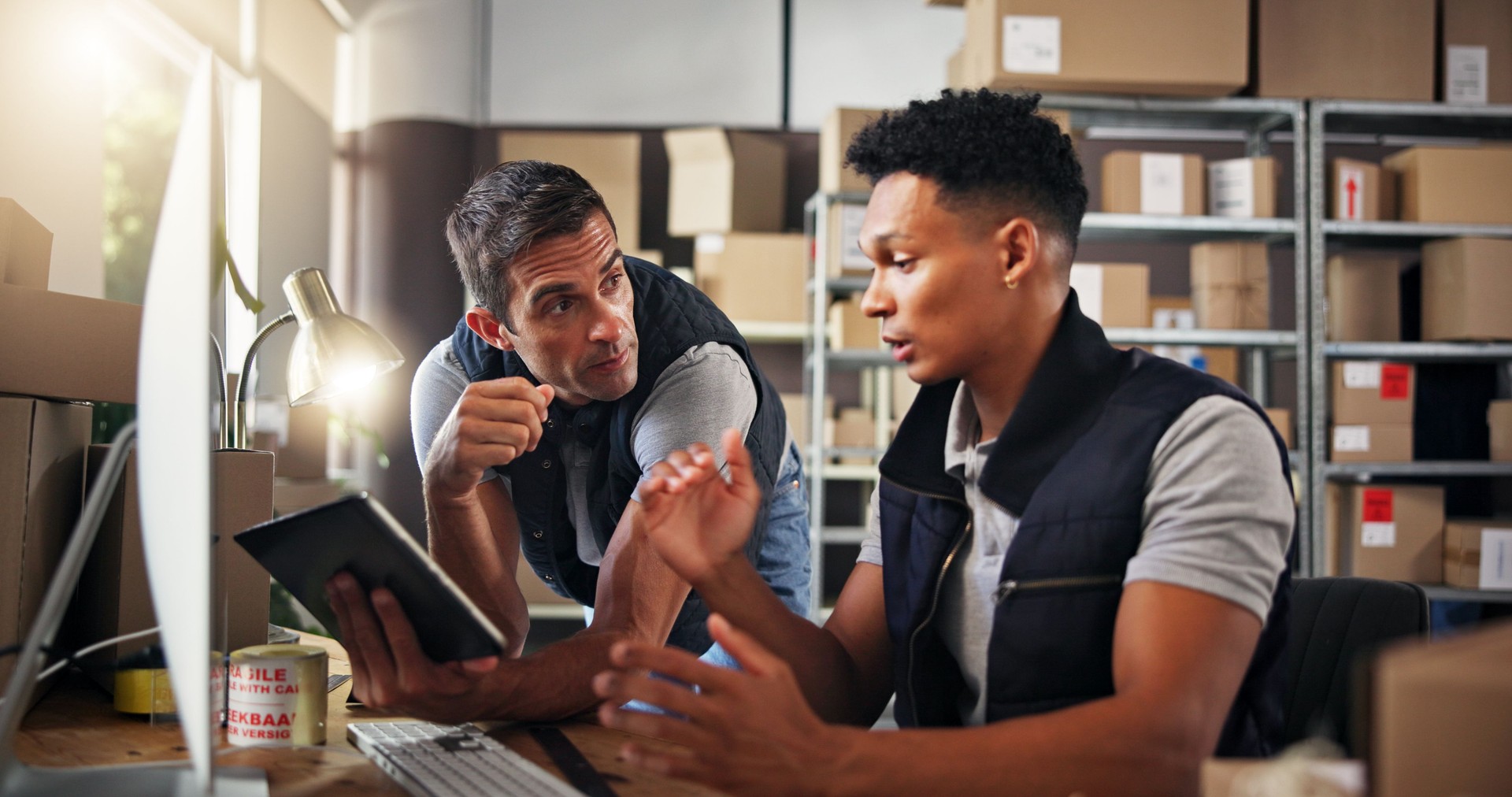 Logistics, people and computer with tablet for discussion, checking stock and inventory research. Team, men and supply chain manager with feedback to monitor distribution, order or business in office